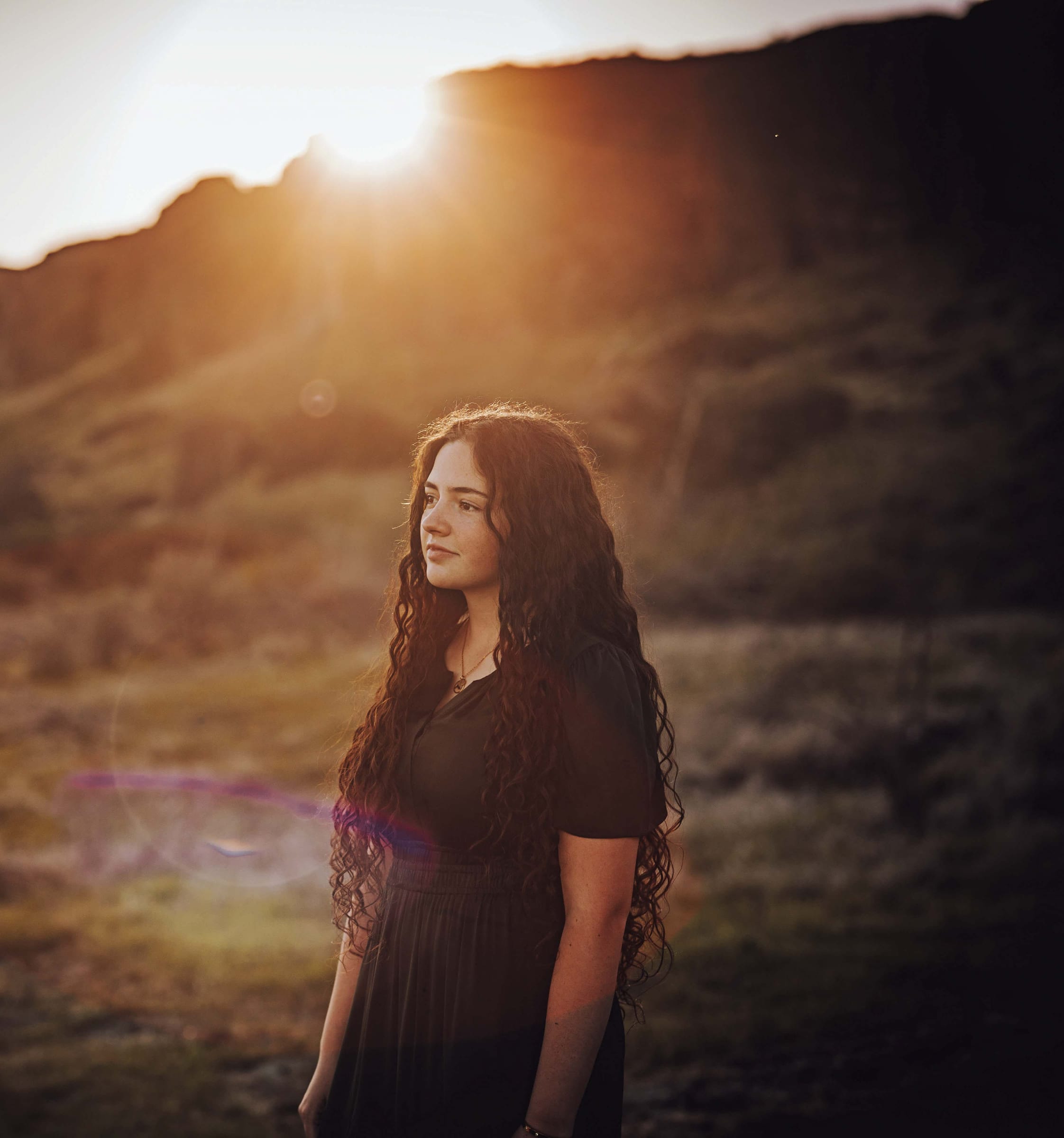 Golden-hour senior portrait of a young woman in a natural outdoor setting, featuring warm sunset in Benton City Tricities, WA