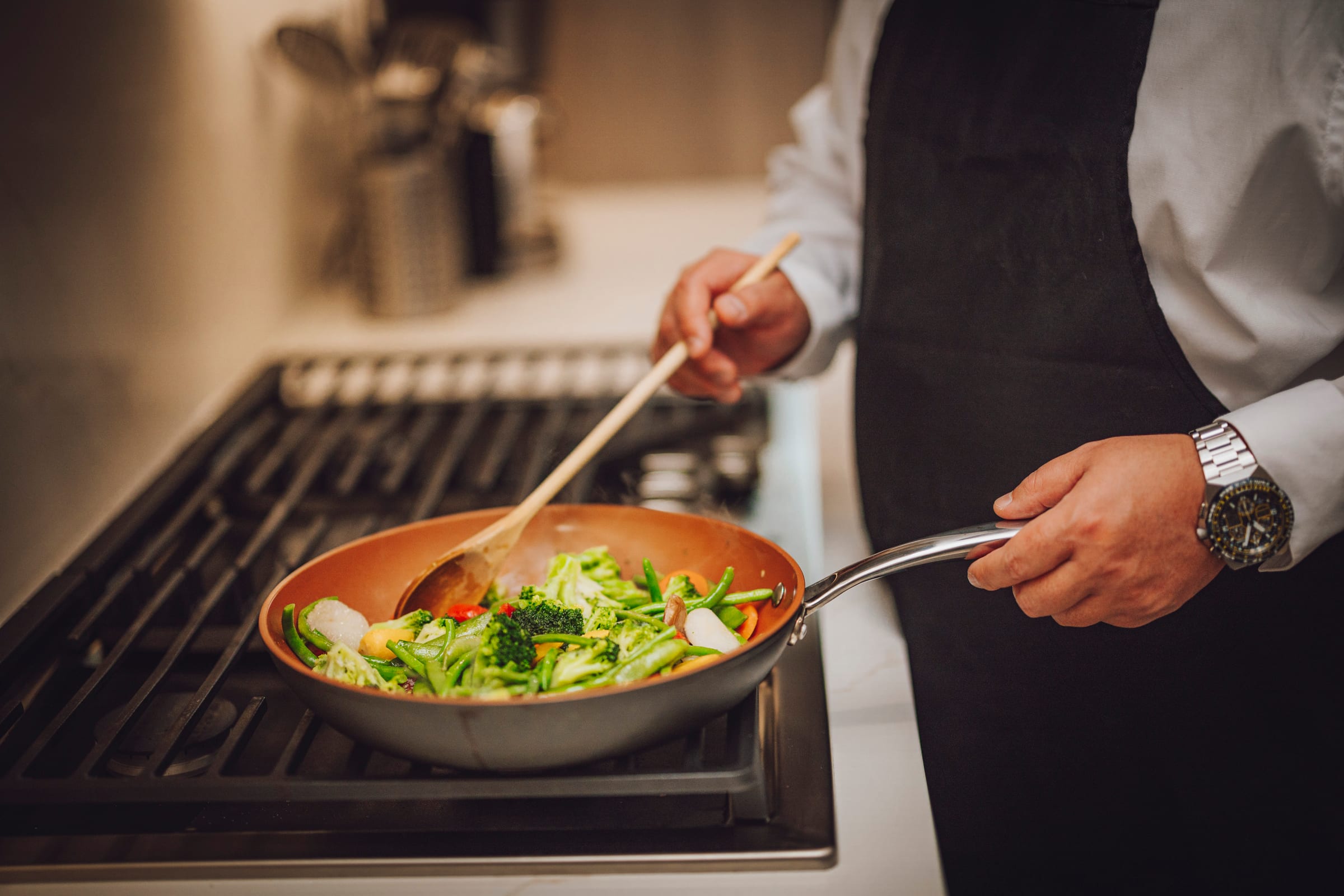Chef stirring vegetables in a pan during a close-up Richland branding photograph.