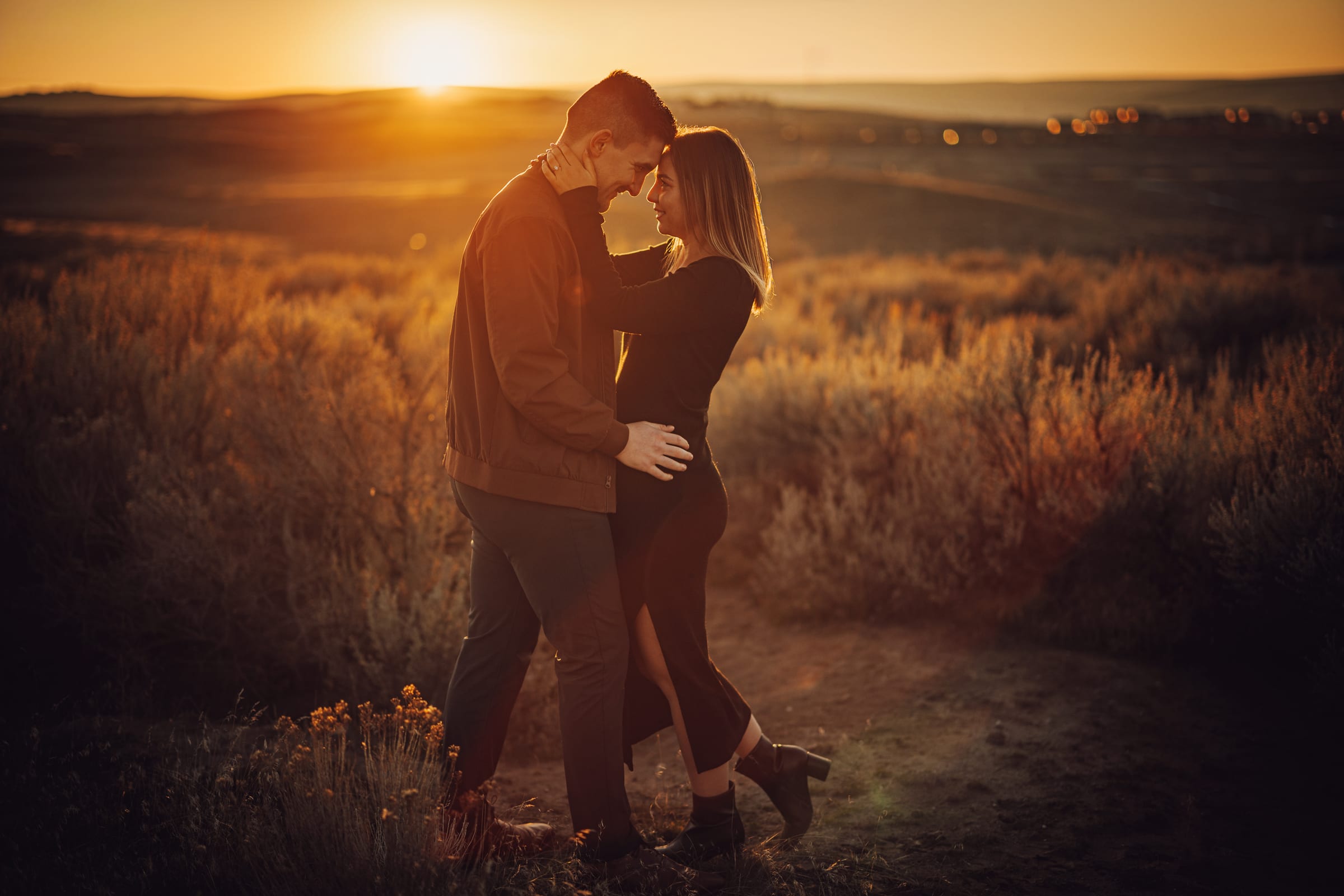 A couple embracing in warm sunset light among open hills.
