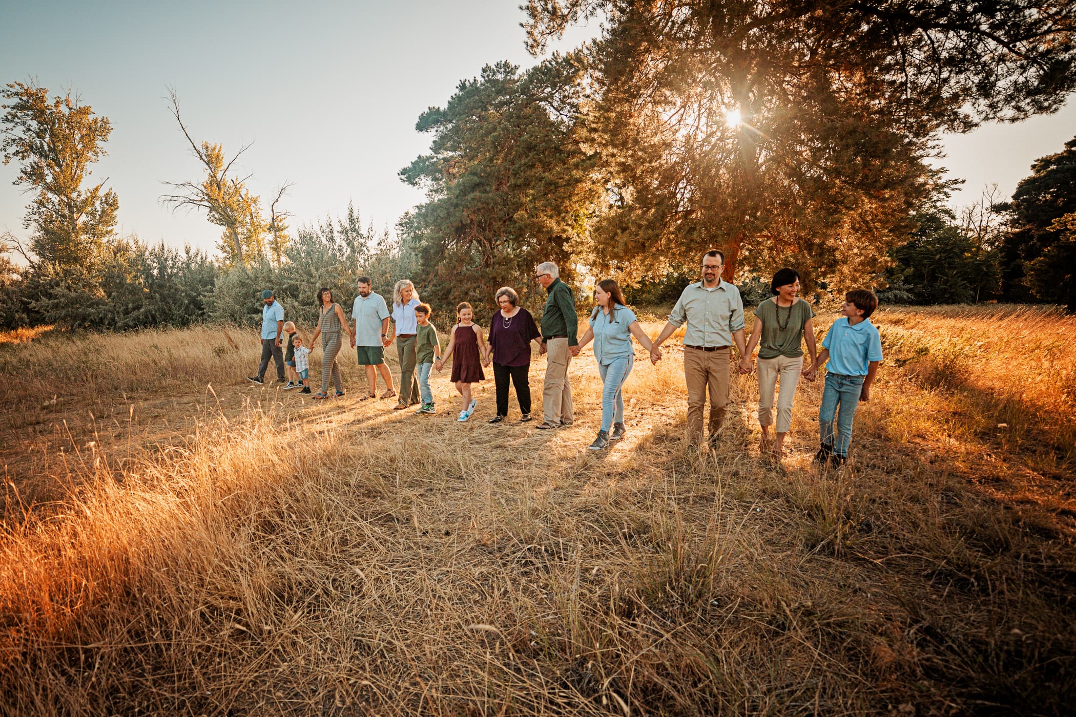 Extended family walking hand in hand across a golden field.