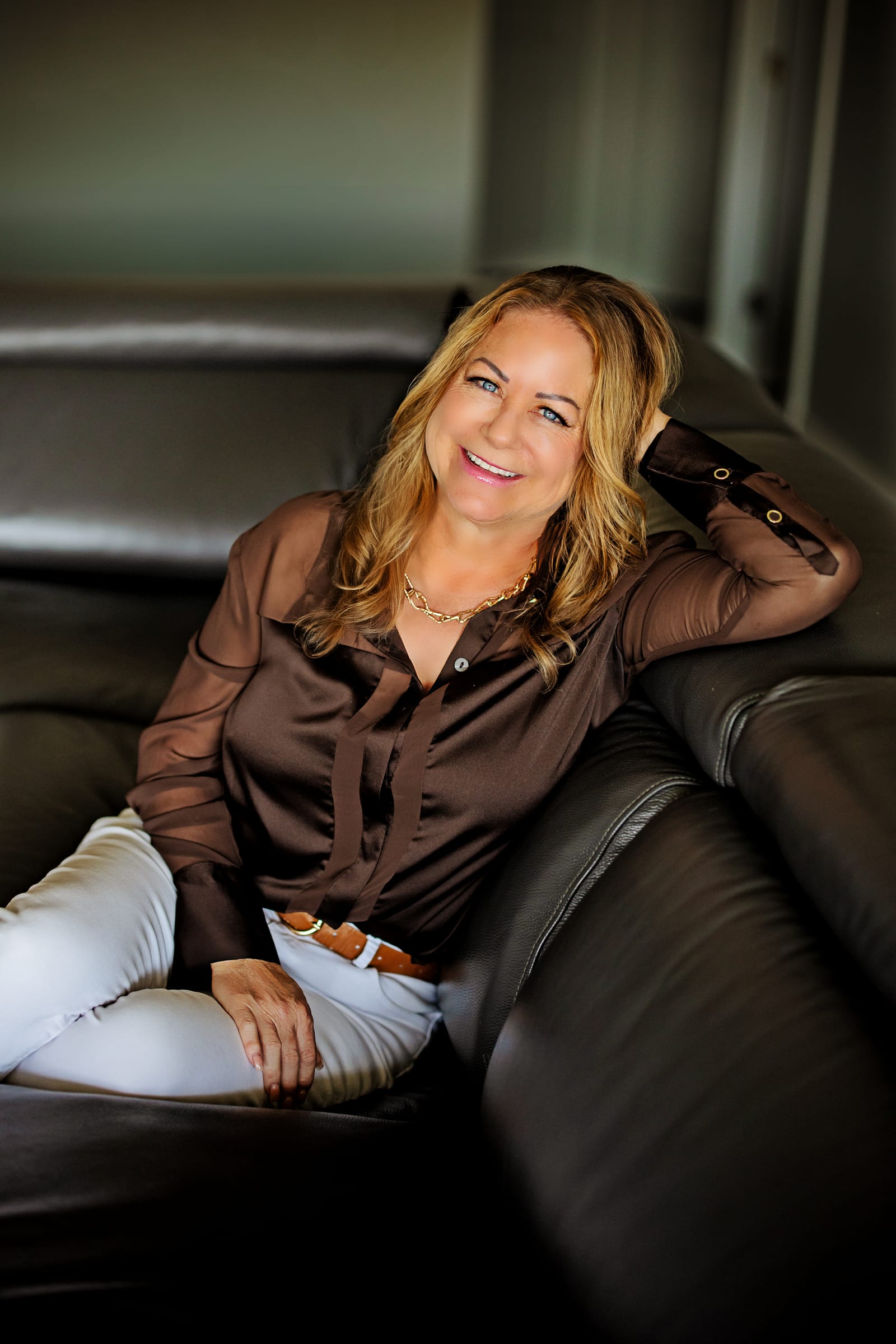 Business owner seated on a black leather sofa during a West Richland branding portrait.