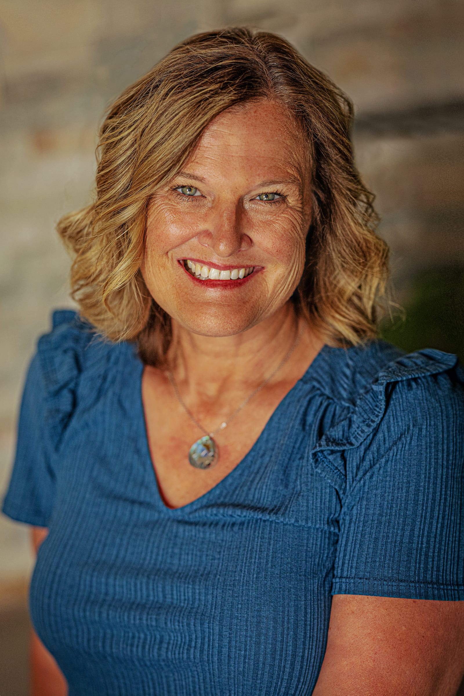 Smiling woman in a blue top photographed during a Kennewick team headshot session.