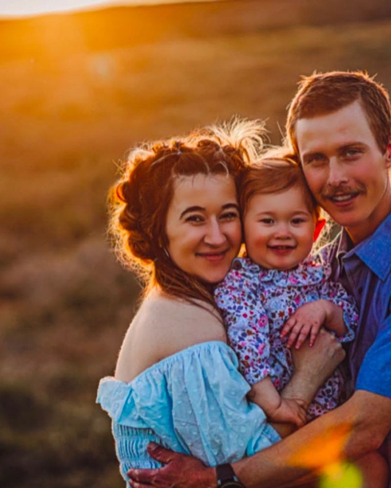 Parents holding their toddler during a family session at golden hour