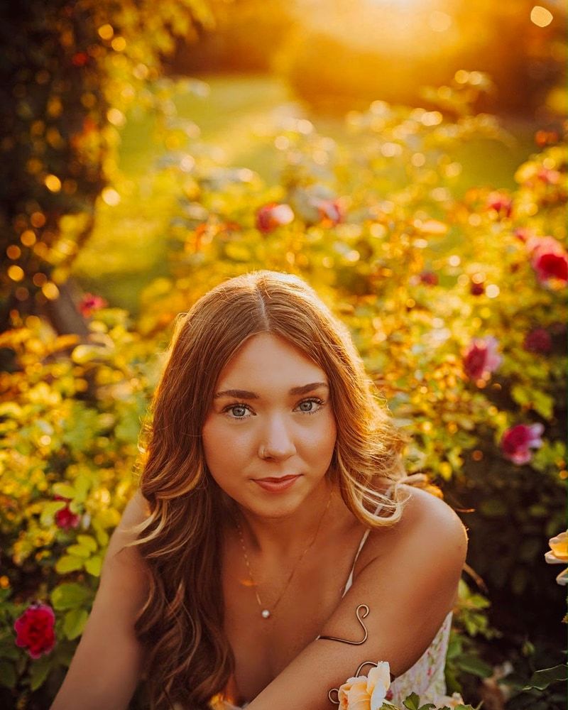 High school senior surrounded by flowers in warm evening light in the Tri-Cities