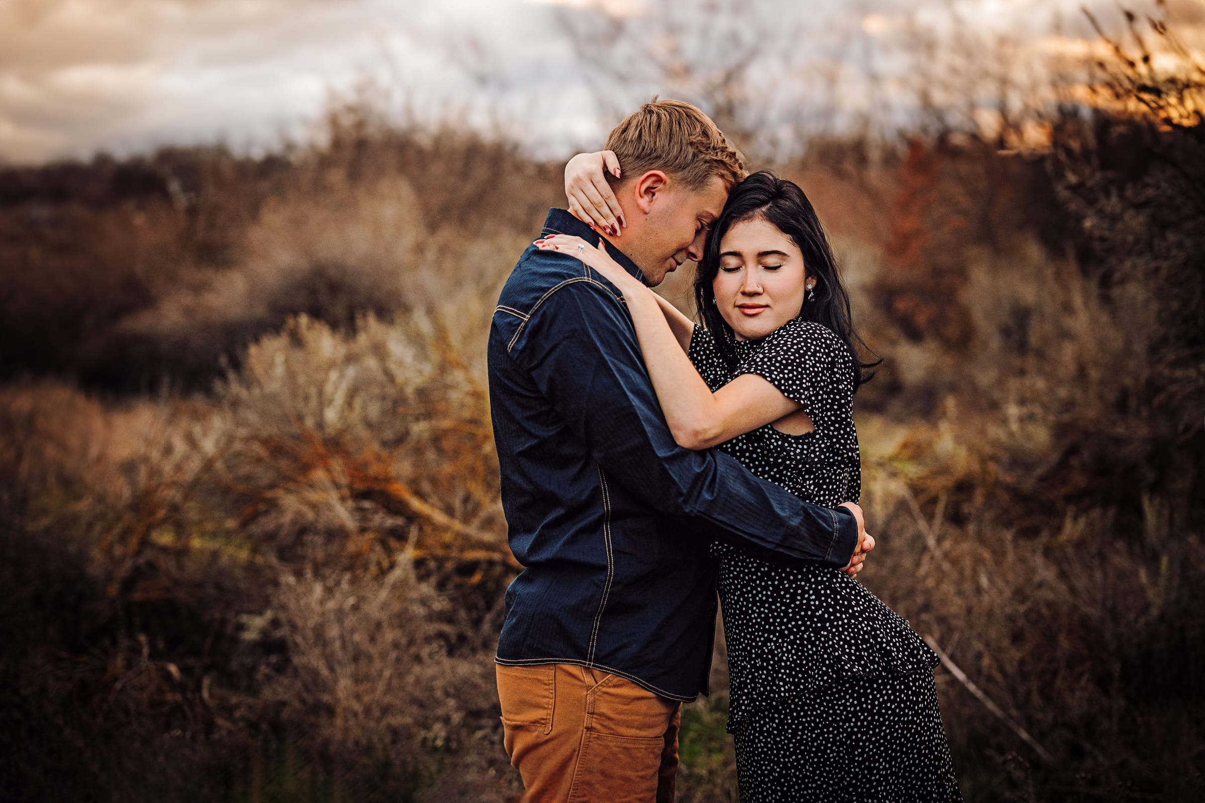 Couple embracing in dry winter grass.