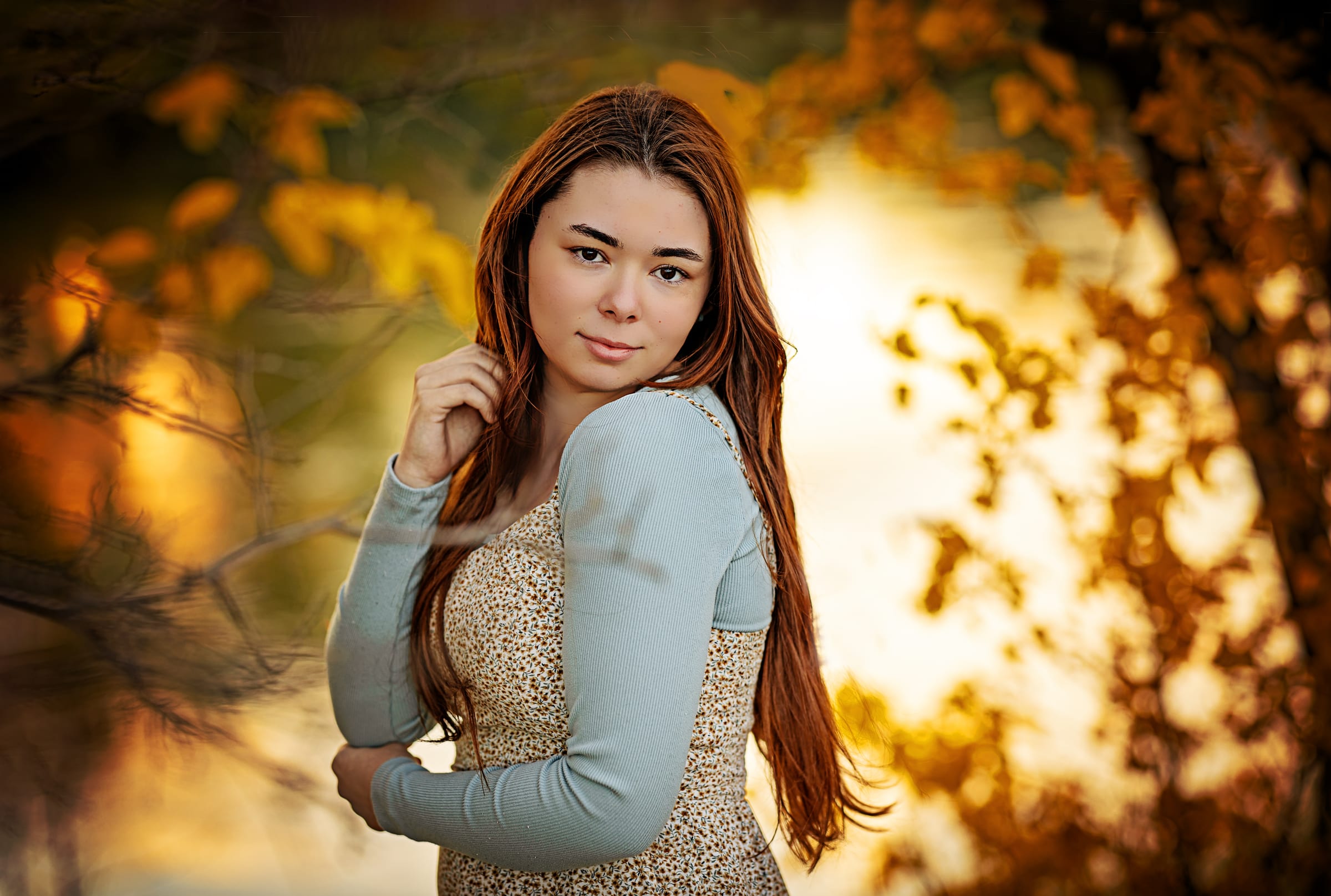 High school senior standing in front of golden autumn foliage.